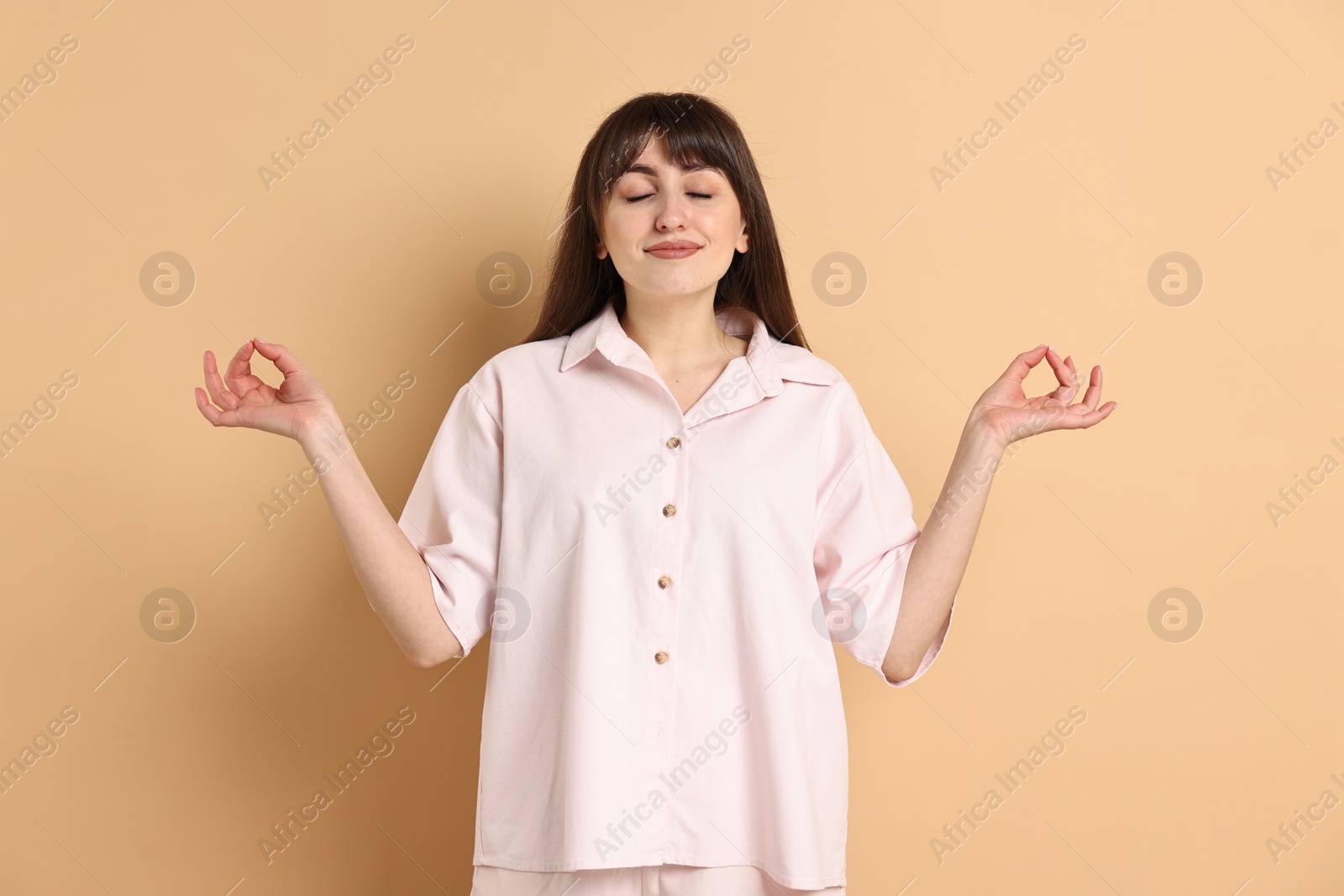 Photo of Woman in pyjama meditating on beige background