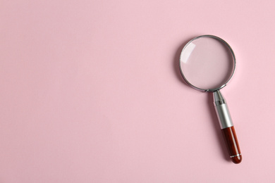 Photo of Top view of magnifying glass on pink background, space for text. Search concept
