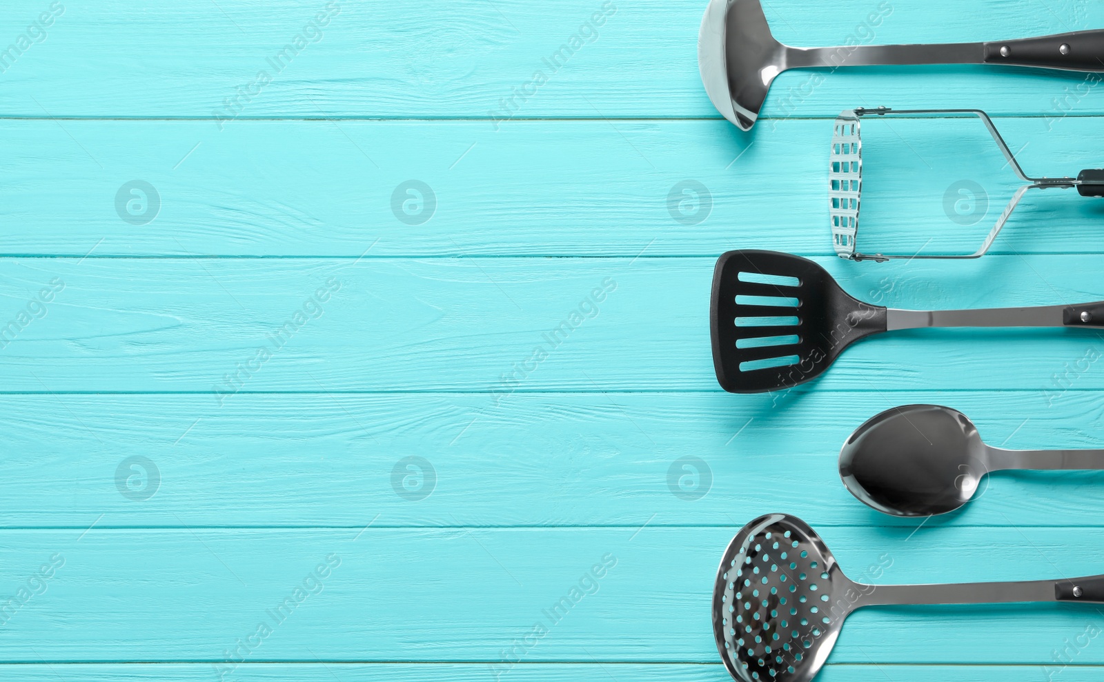 Photo of Set of modern cooking utensils on light blue wooden table, flat lay. Space for text