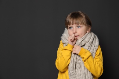 Cute little girl coughing against dark background. Space for text