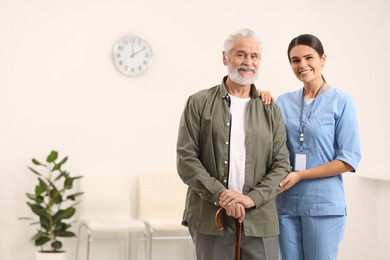 Photo of Smiling nurse with elderly patient in hospital, space for text