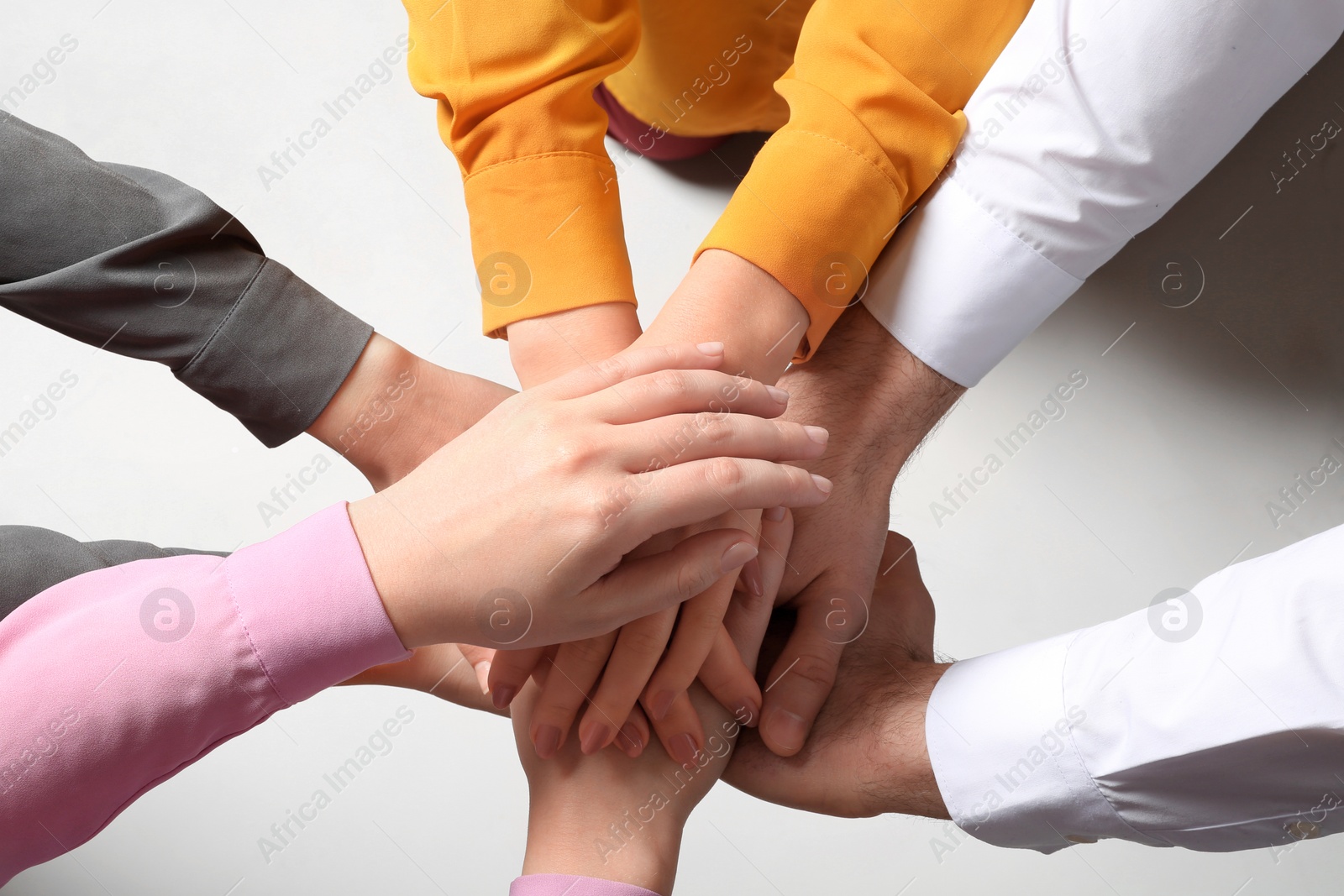 Photo of Young people putting their hands together on white background, top view