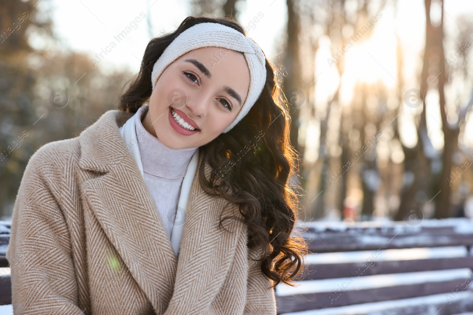 Photo of Portrait of smiling woman in sunny snowy park. Space for text