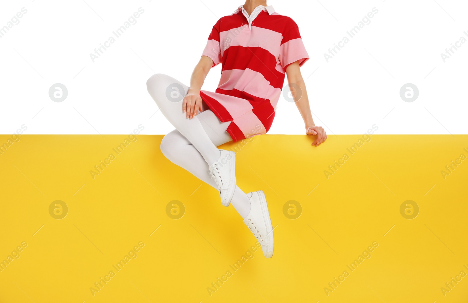 Photo of Woman wearing white tights and stylish shoes sitting on color background, closeup