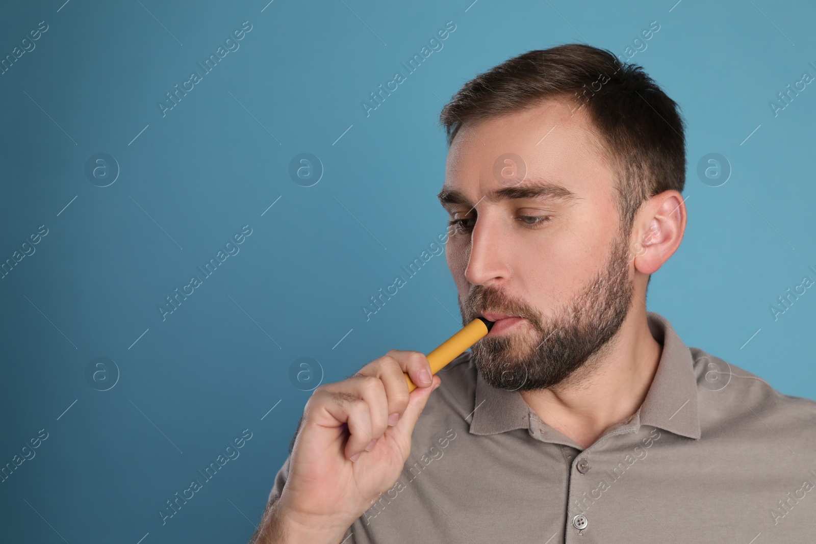 Photo of Man using electronic cigarette on light blue background. Space for text