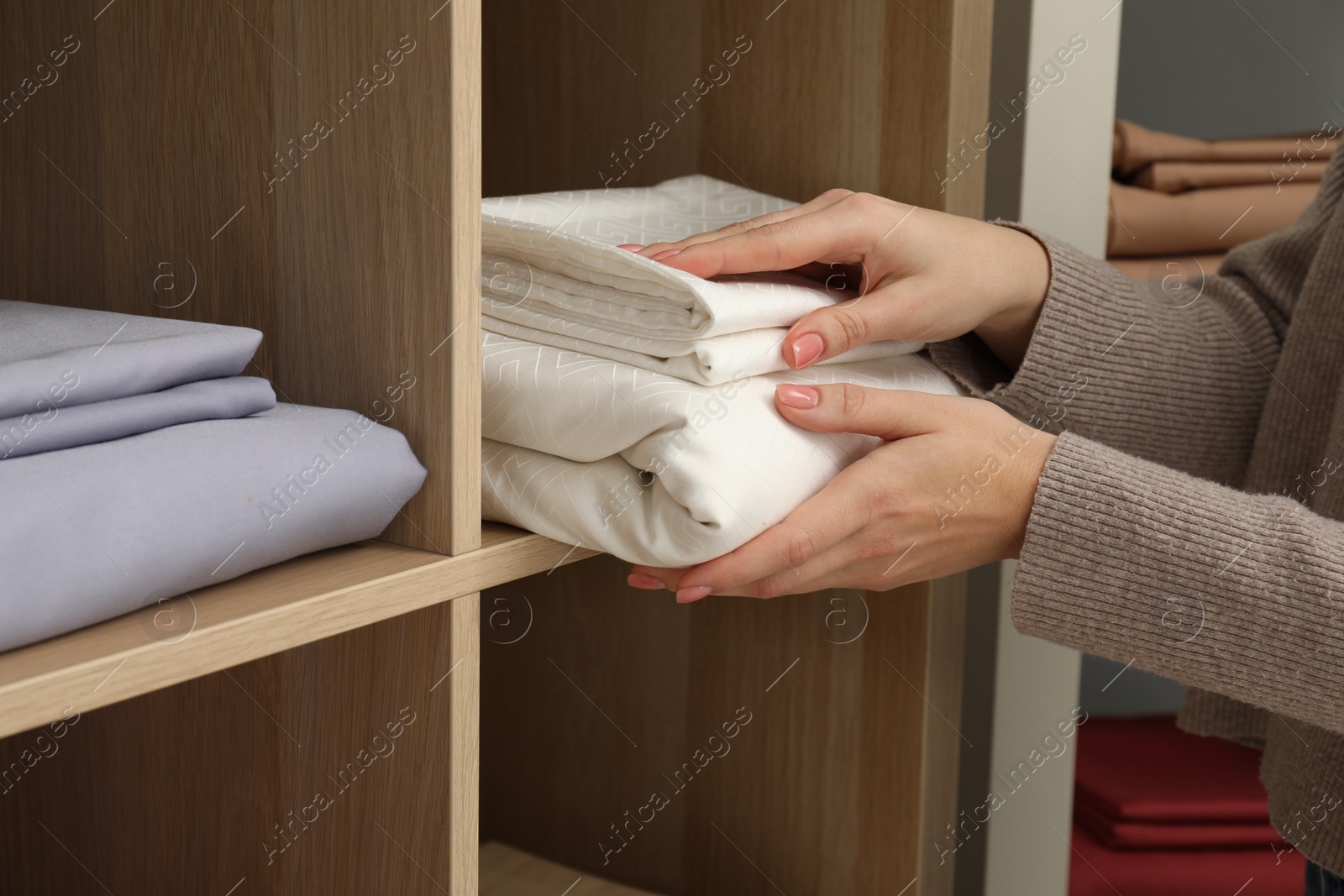 Photo of Woman taking stack of bed linens in shop, closeup