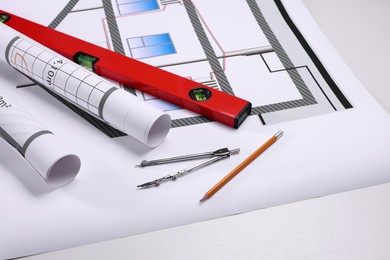 Photo of Construction drawings, pair of compasses, pencil and bubble level on white background