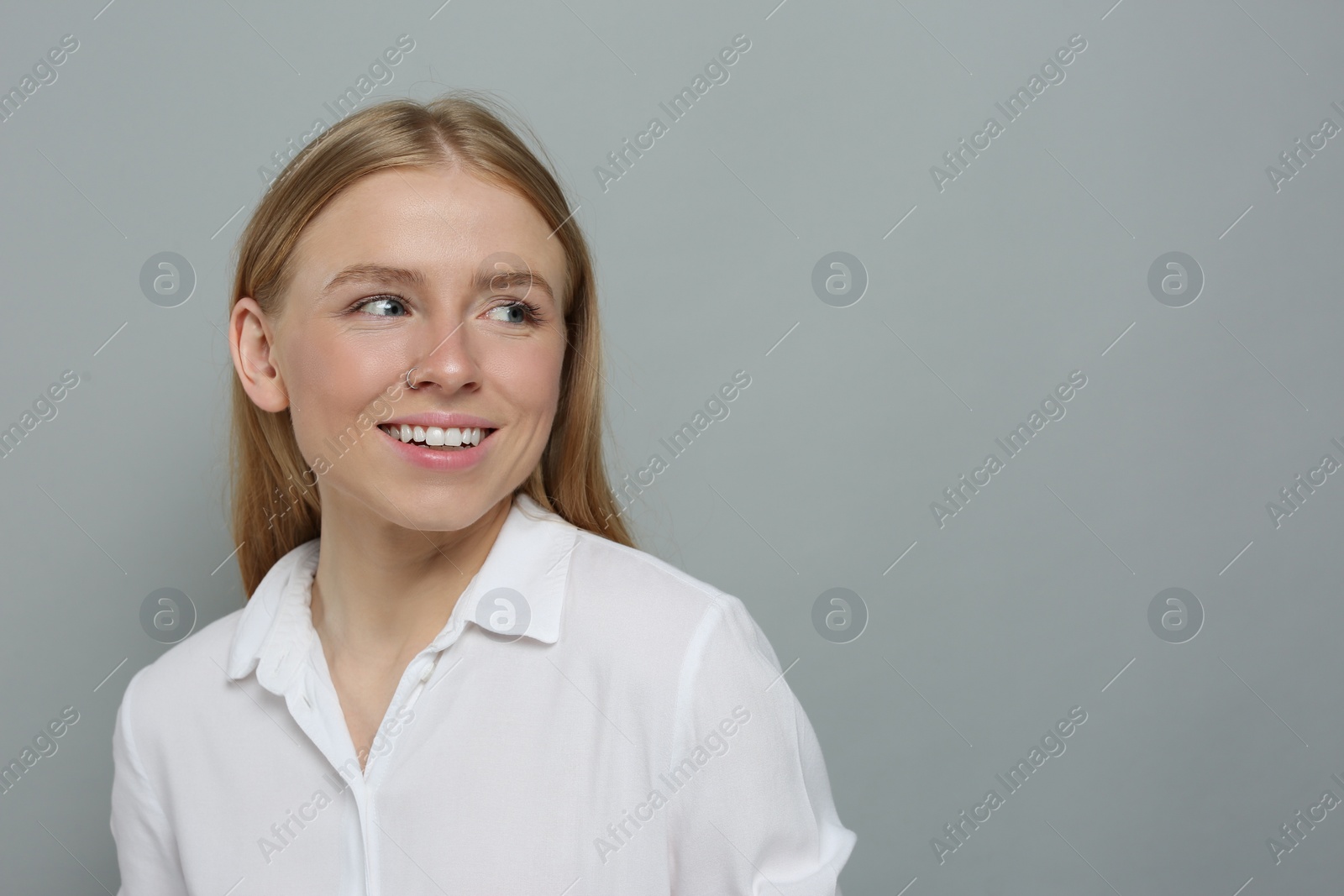 Photo of Portrait of beautiful young woman in white shirt on grey background. Space for text