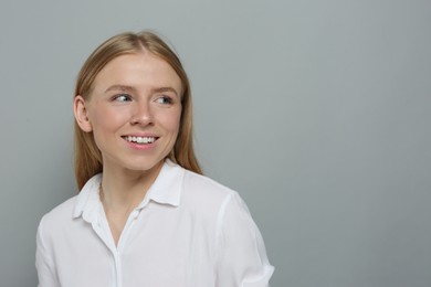 Photo of Portrait of beautiful young woman in white shirt on grey background. Space for text