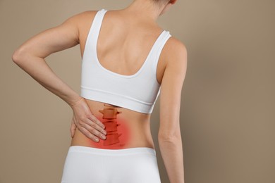 Woman suffering from pain in back on beige background, closeup