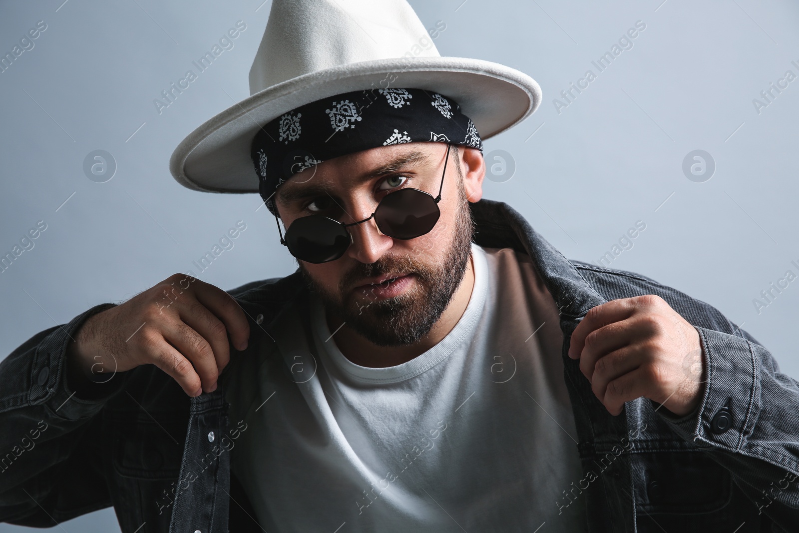 Photo of Fashionable young man in stylish outfit with bandana on grey background