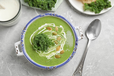 Photo of Tasty kale soup served on light grey marble table, flat lay
