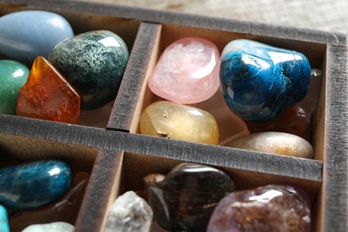 Photo of Box with different beautiful gemstones on table, closeup