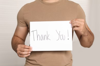 Photo of Man holding card with phrase Thank You indoors, closeup