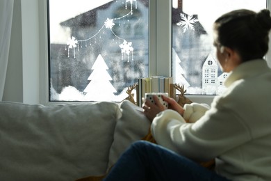 Photo of Woman with hot drink on sofa near beautifully decorated window at home