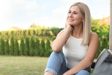 Photo of Portrait of beautiful woman sitting near house in yard, space for text