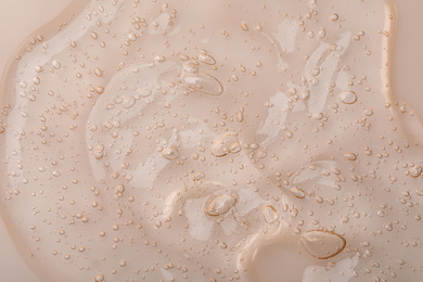 Photo of Pure transparent cosmetic gel on beige background, closeup