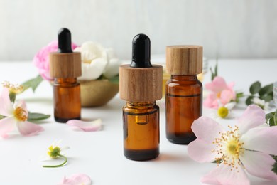 Photo of Aromatherapy. Essential oils and flowers on white table, closeup