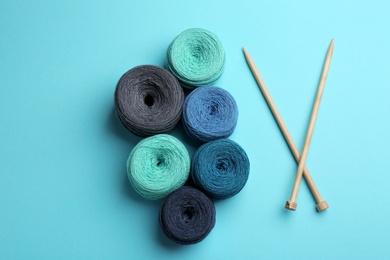 Photo of Clews of threads and knitting needles on color background, flat lay. Sewing stuff