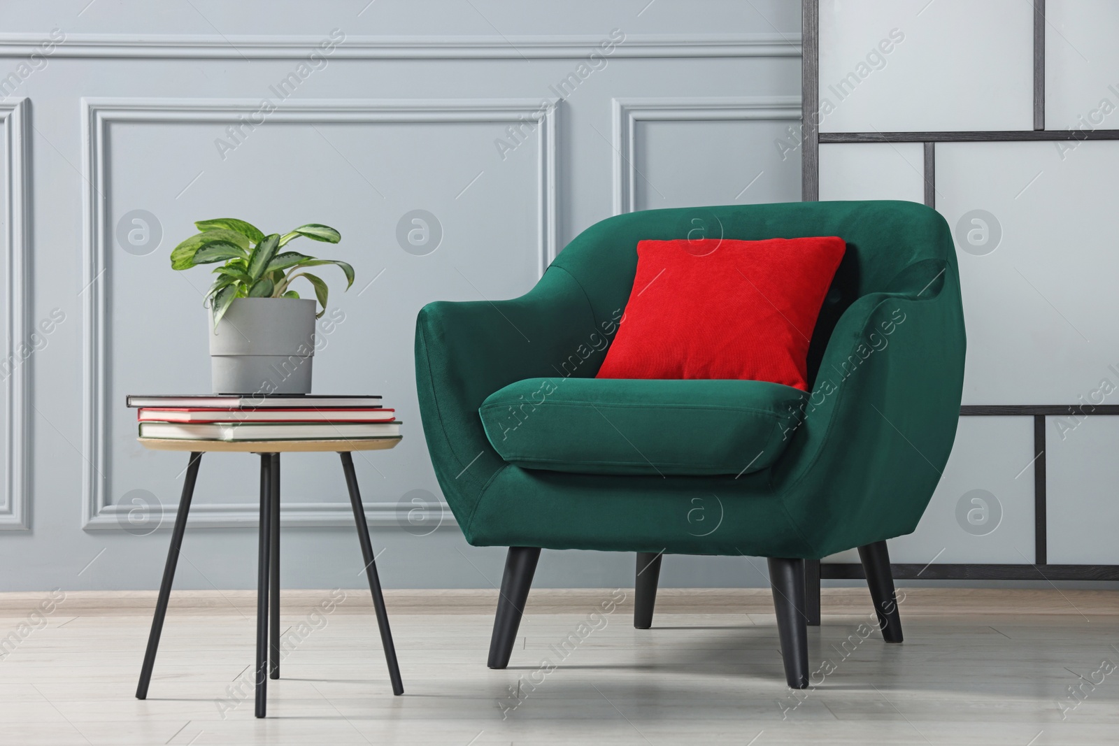 Photo of Stylish armchair and side table with houseplant near light grey wall indoors. Interior design