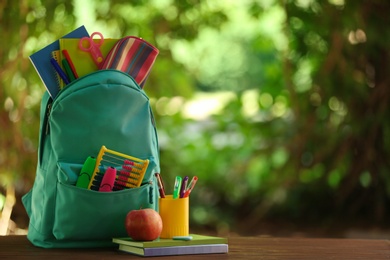 Photo of Color backpack and school stationery on table against blurred background, space for text