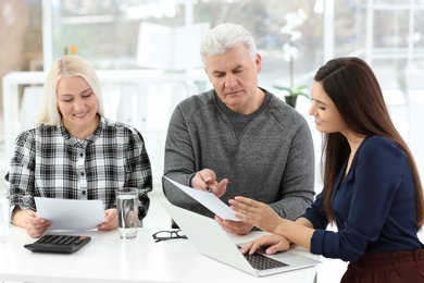 Photo of Mature couple discussing pension with consultant in office