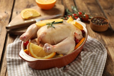 Photo of Chicken with orange slices and other ingredients on wooden table
