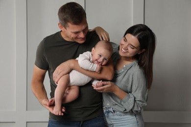 Photo of Happy family. Couple with their cute baby near light wall