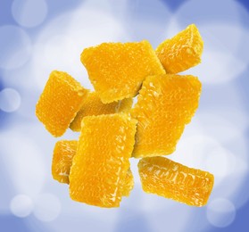 Image of Pieces of honeycomb falling on blue background, bokeh effect