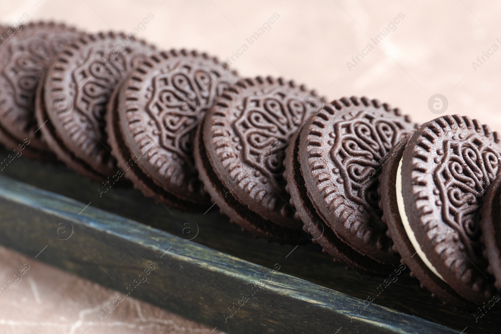 Photo of Tasty chocolate cookies with cream in wooden box, closeup