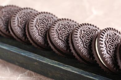Photo of Tasty chocolate cookies with cream in wooden box, closeup