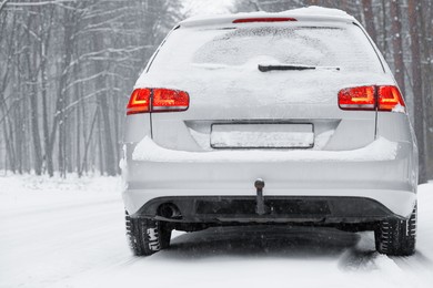 Photo of Car with winter tires on snowy road in forest