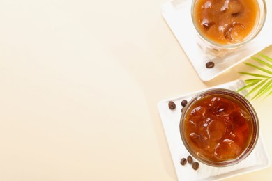 Photo of Refreshing iced coffee with milk in glasses on beige table, flat lay. Space for text