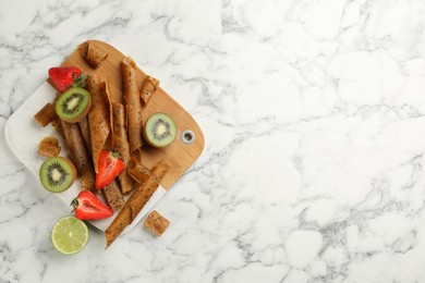 Photo of Flat lay composition with delicious fruit leather rolls on white marble table. Space for text