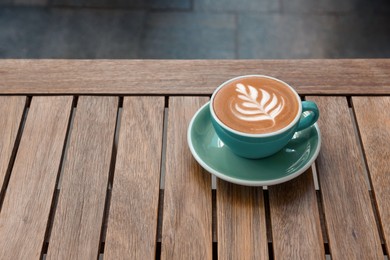 Photo of Cup of aromatic hot coffee on wooden table outdoors, space for text