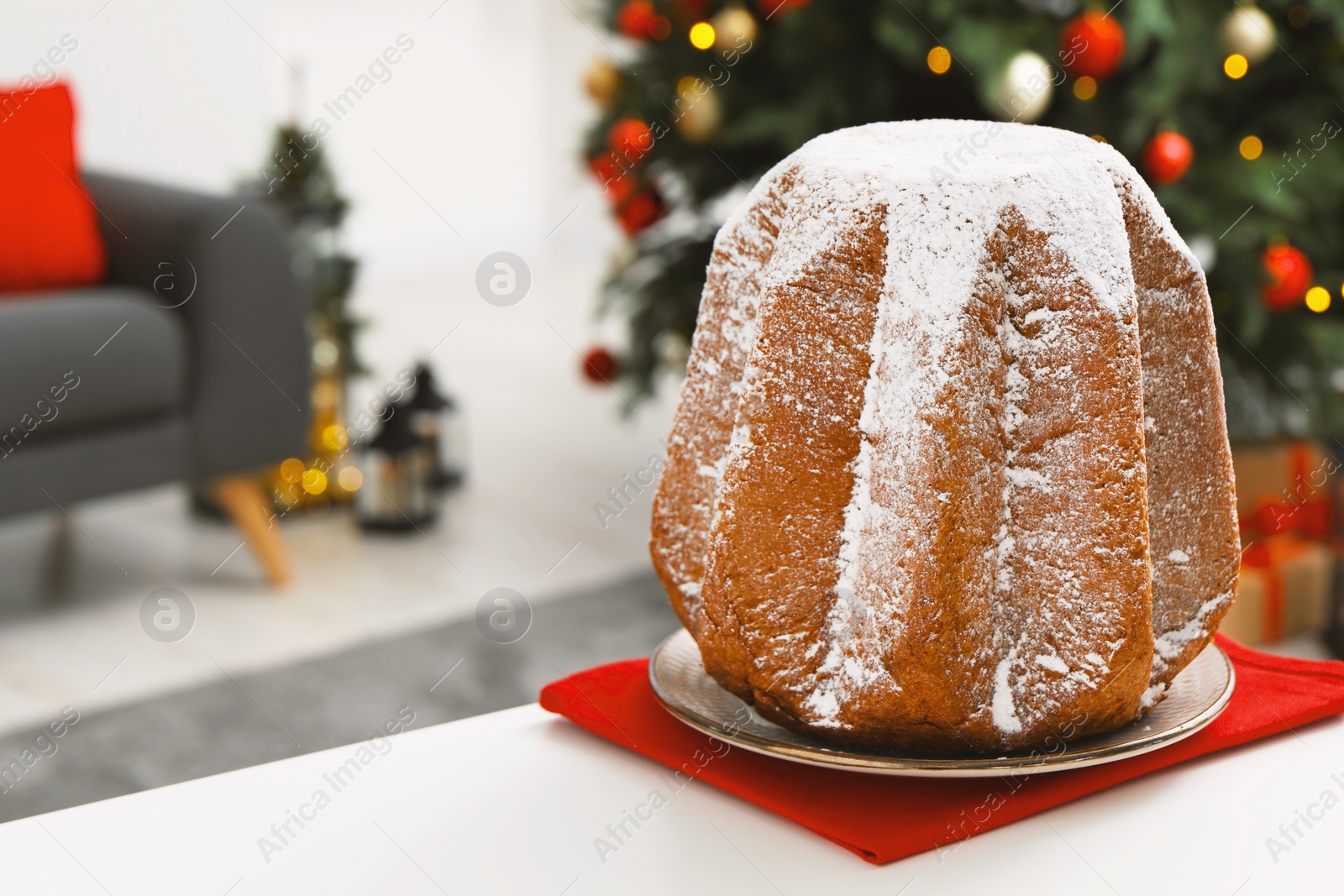 Photo of Traditional Italian pastry. Delicious Pandoro cake with powdered sugar on white table in room, space for text
