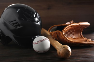Photo of Baseball glove, bat, ball and batting helmet on wooden table