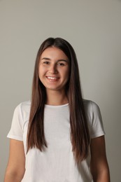 Photo of Smiling young woman in white t-shirt on light background