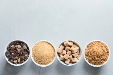 Photo of Bowls with different types of sugar on gray background