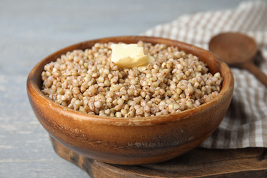 Tasty buckwheat porridge with butter on wooden board, closeup