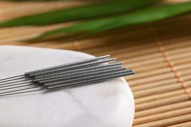 Photo of Stone with acupuncture needles on bamboo mat, closeup