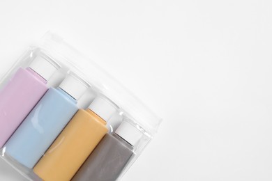 Photo of Cosmetic travel kit in plastic bag on white background, top view. Space for text