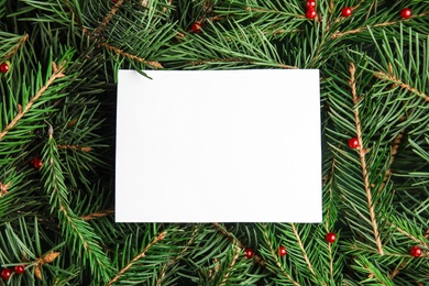 Photo of Blank card on Christmas tree branches as background, top view. Space for text