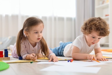 Photo of Cute little children drawing on floor in kindergarten