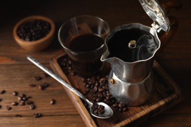 Photo of Brewed coffee, moka pot and beans on wooden table