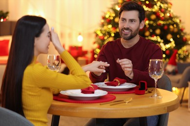 Making proposal. Man putting engagement ring on his girlfriend's finger at home on Christmas, selective focus