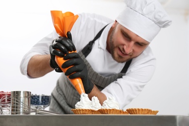 Photo of Pastry chef preparing desserts at table in kitchen