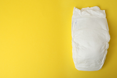 Photo of Baby diaper on yellow background, top view. Space for text