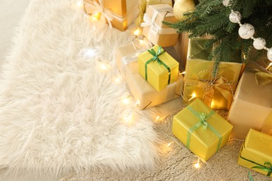 Photo of Decorated Christmas tree, beautiful gift boxes and festive lights indoors, space for text