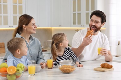 Photo of Happy family having breakfast at table in kitchen